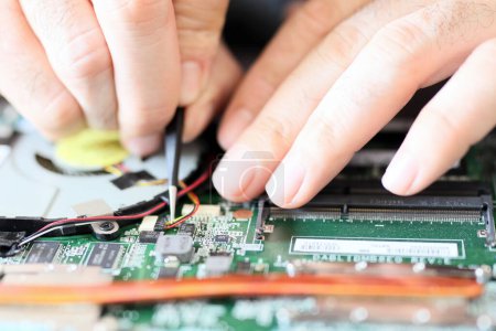 Téléchargez les photos : Expert is repairing to inner of laptop with screwdriver. The design restrictions on power, size, and cooling of laptops limit the maximum performance of laptop parts compared. - en image libre de droit