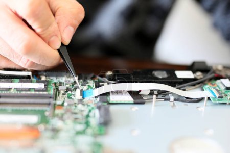 Photo for Expert is repairing to inner of laptop with screwdriver. The design restrictions on power, size, and cooling of laptops limit the maximum performance of laptop parts compared. - Royalty Free Image