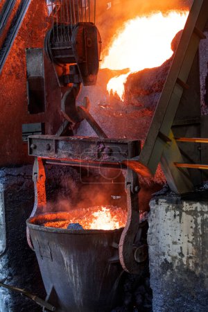Photo for Molten copper is pouring to melting pot. Combining copper with tin and/or arsenic in the right proportions produces bronze, an alloy that is significantly harder than copper. - Royalty Free Image