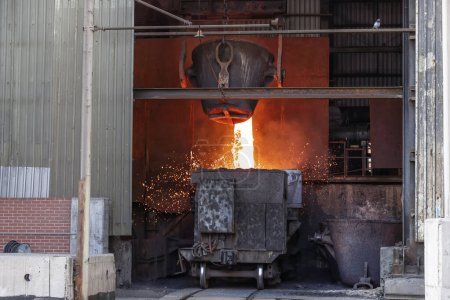 Foto de Iron and steel smelting process in a metallurgical plant. The hot slag of the copper is pouring to the large melting pot. - Imagen libre de derechos
