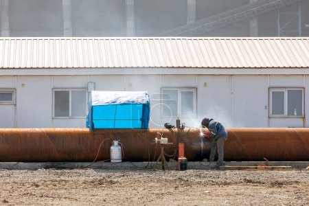 Photo for The welder is welding with covered electrode process on the pipeline in the construction site. - Royalty Free Image
