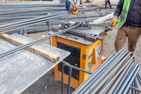 Construction worker is bending to rebars with tool. Rebar, also known as reinforcement steel and reinforcing steel, is a steel bar of steel wires used in reinforced concrete and masonry structures.