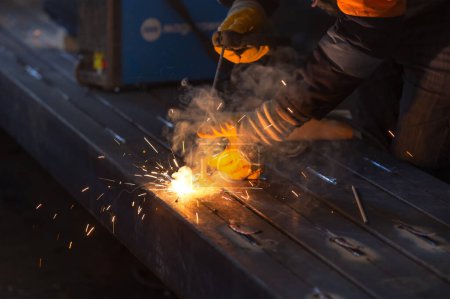 Photo for The welder is welding with shielded metal arc welding, manual metal arc welding or stick welding. Electric current is used to strike an arc between the base material and consumable electrode rod. - Royalty Free Image