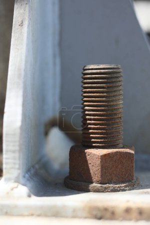 Photo for A rusty steel anchor bolt on the flange of the structure steel. Anchor bolts are used to connect structural and non-structural elements to concrete. - Royalty Free Image