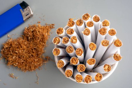 Photo for Cigarettes in a white ashtray and lighter on a gray background - Royalty Free Image