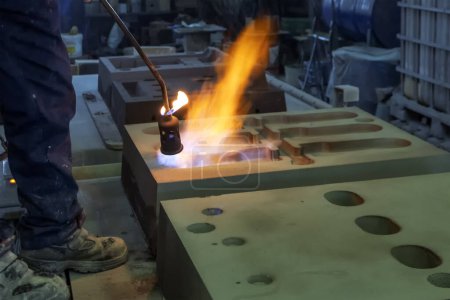 The worker is preheating to mold for casting. Sand casting, also known as sand molded casting, is a metal casting process characterized by using sand as the mold material.