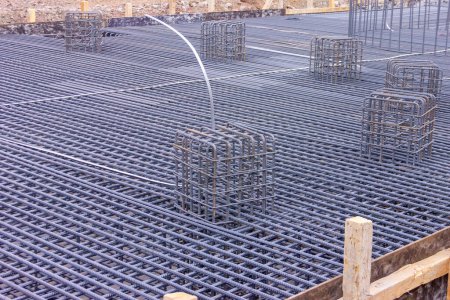 Photo for View of the rebar beam cages on the foundation for concrete and a new industrial plant. A tied rebar beam cage. This will be embedded inside cast concrete to increase its tensile strength. - Royalty Free Image