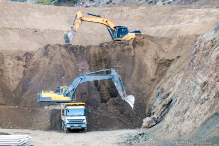Foto de Las excavadoras están excavando y cargando a un camión volquete en el sitio de construcción. - Imagen libre de derechos