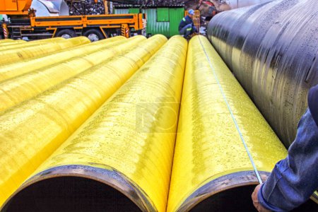 Téléchargez les photos : Les travailleurs mesurent sur des tuyaux recouverts de polyéthylène dans l'usine. - en image libre de droit