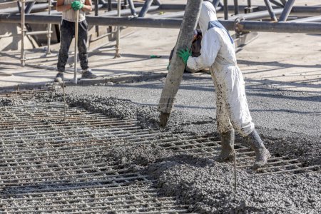 Pouring and smoothing out concrete with ready-mix concrete (RMC) in the construction site. It is concrete that is manufactured in a batch plant, according to a set engineered mix design.