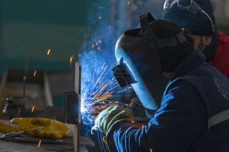 Foto de El soldador está soldando un acero estructural con soldadura de arco metálico de gas (GMAW) en el taller. - Imagen libre de derechos