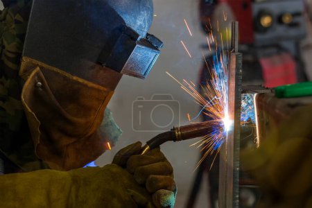Téléchargez les photos : Le soudeur soude un acier de construction avec soudure à l'arc métallique au gaz (GMAW) dans l'atelier. - en image libre de droit