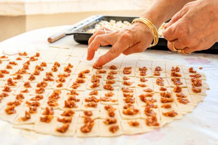 Foto de Una ama de casa haciendo ravioles turcos. Es un tipo de albóndigas popular en la mayoría de las cocinas túrquicas, así como en las cocinas del Cáucaso Meridional, Asia Central, Afganistán. - Imagen libre de derechos