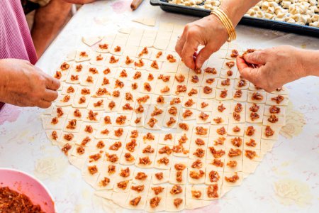 Photo for Housewives preparing meat ravioli. A popular type of Turkish manti is known as Kayseri mantisi, originally from Kayseri, an Anatolian city. - Royalty Free Image