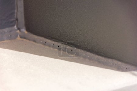 Foto de Vista de las porosidades en el filete de soldadura de metal después de la pintura. Un defecto de soldadura es cualquier defecto que compromete la utilidad de una soldadura. Hay una gran variedad de defectos de soldadura. Las imperfecciones de soldadura se clasifican según ISO 6520. - Imagen libre de derechos