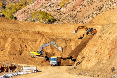 Foto de Las excavadoras están excavando y cargando tierra a los camiones en el sitio de construcción. - Imagen libre de derechos