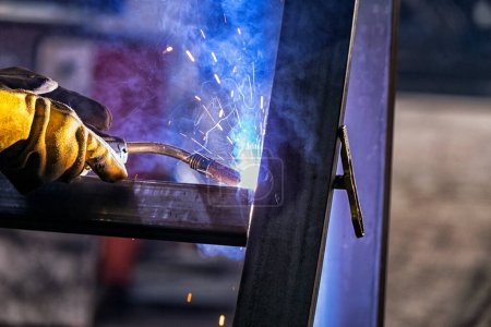 Foto de El soldador está soldando un acero estructural con soldadura de arco metálico de gas (GMAW) en el taller. - Imagen libre de derechos