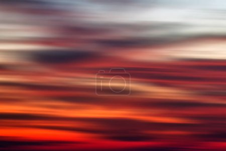 Photo for Background of the motion blurry red, white and black clouds under the beautiful sunset sky. Clouds exert numerous influences on Earth's troposphere and climate. - Royalty Free Image