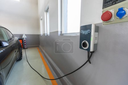 Photo for Electric car charging at home. Various methods exist for recharging the batteries of electric cars. Process of discharging involves lithium ions from a positive electrode passing through a separator. Electric car charging at charging station - Royalty Free Image