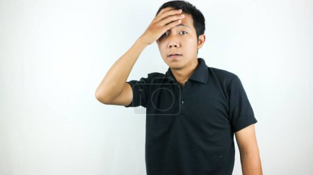 Enttäuschter Gesichtsausdruck eines asiatischen Mannes, der auf weißem Hintergrund isoliert schlechte Nachrichten am Handy liest. Schlag auf die Stirn.