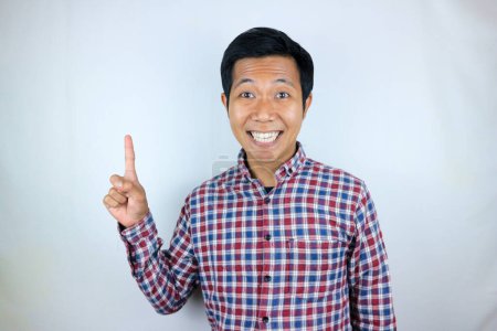 Hombre asiático sonriendo mientras apunta hacia arriba presentando el producto. concepto publicitario