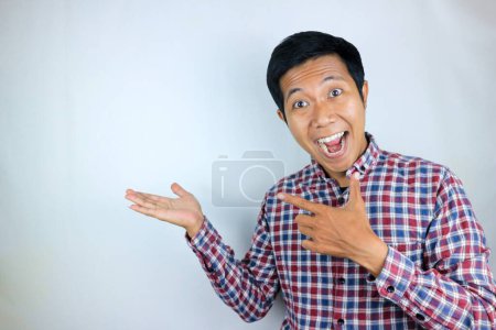Hombre asiático expresión sonriendo mientras señala al lado presentando el producto. concepto publicitario