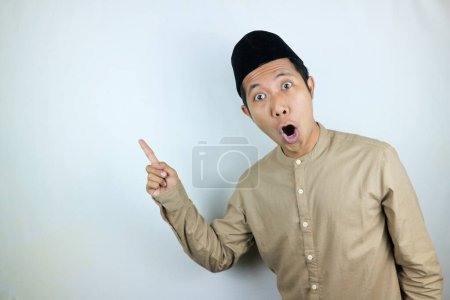 divertido facial expresión shocked y sorpresa asiático musulmán hombres usando gorra señalando a un lado