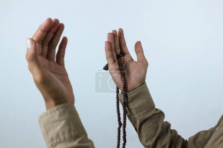 Mano masculina sosteniendo rosario de cuentas de oración sobre fondo blanco. Ramadán kareem y ied concepto mubarak.