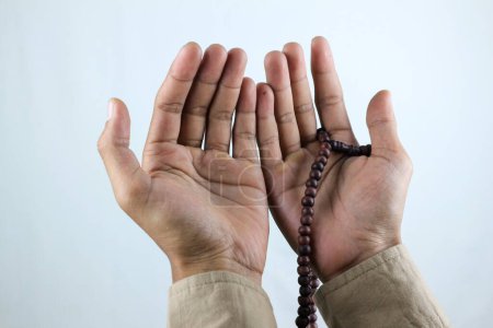 Male hand holding prayer beads rosary on white background. Ramadan kareem and ied mubarak concept.
