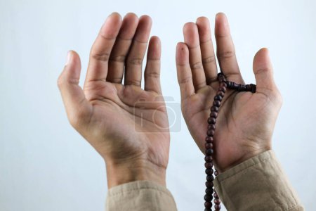 Mano masculina sosteniendo rosario de cuentas de oración sobre fondo blanco. Ramadán kareem y ied concepto mubarak.
