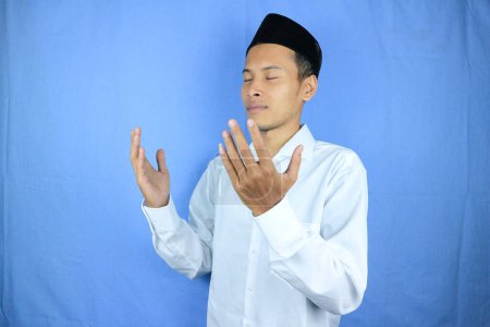 Hombre asiático musulmán sosteniendo cuentas de oración sobre fondo azul. Ramadán kareem y ied concepto mubarak.