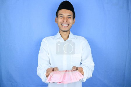 Expresión sonriente del hombre musulmán asiático que da dinero para ayudar, donar o zakat
