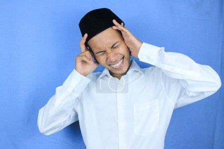 Young muslim asian man having a headache isolated on white background