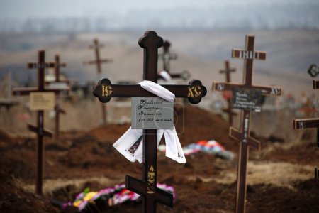 Foto de Bakhmut, UKRAINE JAN 19 2023 New graves of civilians at Bakhmut cemetery against the background of combat actions at Bakhmut, during russian invasion to Ukraine - Imagen libre de derechos
