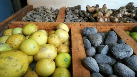 Foto de Kluwek, limón, jengibre, cúrcuma y otras especias se muestran y comercializan en mesas de madera divididas en el mercado tradicional. para el condimento y la salud (hierbas). - Imagen libre de derechos