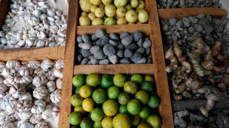 Foto de Ajo, Pangium EModule (Kluwek), Limón se venden en una mesa de madera dividida en los mercados tradicionales. - Imagen libre de derechos