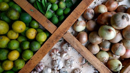 Foto de Las cebollas, limones y limas se venden en mesas de madera divididas en mercados tradicionales.. - Imagen libre de derechos