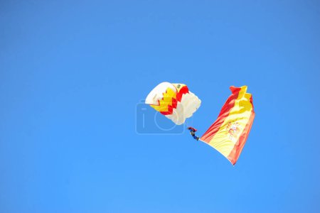 Photo for Corporal  Maria Carmen Gomez landing with a parachute and the flag of Spain  . Some 4,100 military personnel participated during the National Day military parade including King Felipe VI, Queen Letizia, and Princess Leonor, in Madrid Spain. - Royalty Free Image