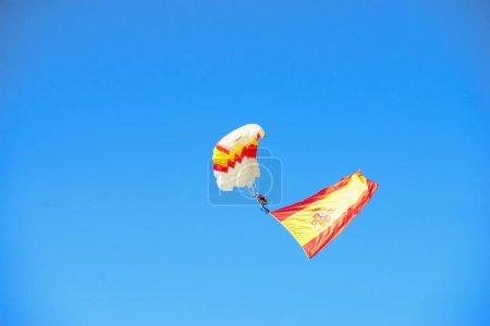 Photo for Corporal  Maria Carmen Gomez landing with a parachute and the flag of Spain  . Some 4,100 military personnel participated during the National Day military parade including King Felipe VI, Queen Letizia, and Princess Leonor, in Madrid Spain. - Royalty Free Image