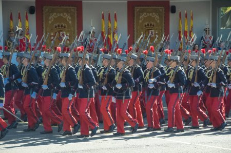 Photo for Marching soldiers wearing black tunic and red trousers, some 4,100 military personnel participated during the National Day military parade including King Felipe VI, Queen Letizia, and Princess Leonor, in Madrid Spain.i - Royalty Free Image