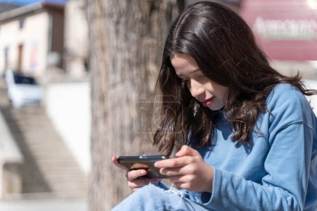 Téléchargez les photos : Fille jouer à des jeux vidéo avec un smartphone - en image libre de droit