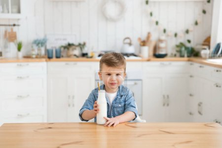 Photo for Cute caucasian child refuses to drink milk or yogurt. Toddler boy drank milk and didnt like it because he felt the medicine hidden there. Child feeding problems. Copy space, Mock up. - Royalty Free Image