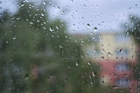 Photo for Rain drops on a window glass during a summer storm. Moody, melancholic, nostalgic, and slightly sad feelings concept. Shallow depth of field, blurry outside background. - Royalty Free Image