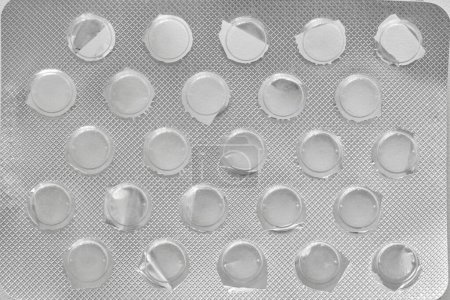 Silver pills blister pack without tablets. Top view food supplements empty packaging. Medicine shortage concept. Running out of drugs. Close-up macro image.