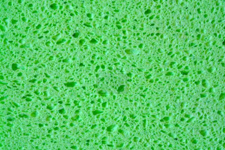 Esponja verde con fondo de textura de poros para gráficos. Fotografía macro de cerca del tejido esponjoso doméstico.