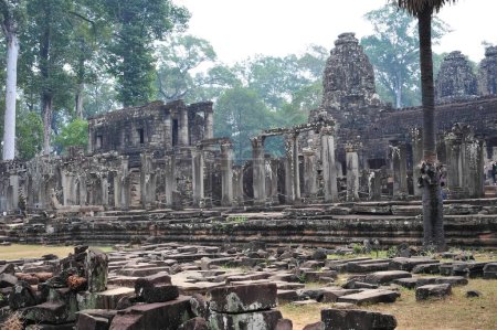 Historic view of Angkor Wat ruins surrounded by verdant trees in Siem Reap, Cambodia. A cultural and architectural marvel dating back centuries.