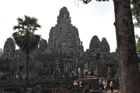 Los visitantes pasean entre las ruinas históricas de Angkor Wat, el icónico complejo de templos de Camboya. Una mezcla de arquitectura religiosa y exuberante vegetación los rodea.