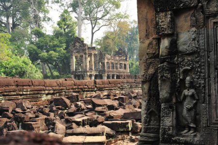 Un gran edificio de piedra con una estatua de una mujer en ella en Siem Reap Angkor Wat Camboya. El edificio está rodeado de escombros y desechos.