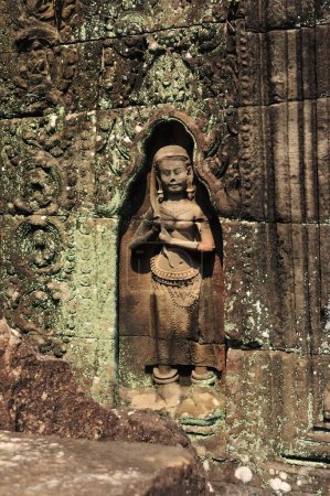 Detailed view of a weathered stone statue carved into the wall of Angkor Wat, showcasing traditional Khmer art in Siem Reap, Cambodia.