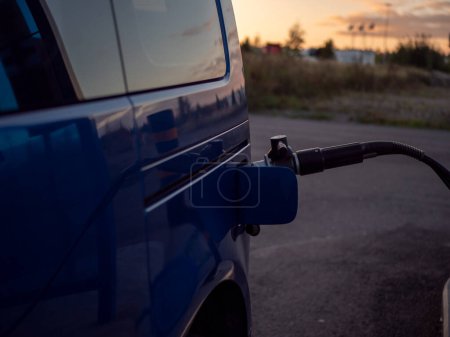  a gas nozzle of a compressed natural gas CNG powered car with sunset on the background. High quality photo